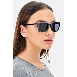 Een vrouw met een donkere zonneleesbril, schuin aanzicht
