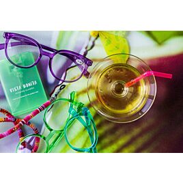 Een aantal leesbrillen op een tafel met glazen en kleurrijke spullen.